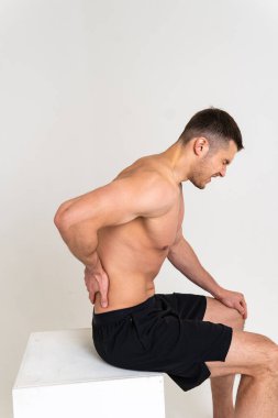 Bir erkek arkasını yaslar elini sırtına koyar. Ağrılı, kramplı omurga izole edilmiş stres, insan gerilimi bakımı, sırt ağrısı çekici.