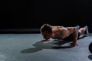 Siyah arka plandaki adam fitness kaslarını şişirmeye devam ediyor seksi siyah, kol eğitimli adam ağır, çekici cilt metali, insan formunda şınav.