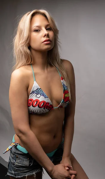 Menina mantém a cabeça contra um belo fundo branco um belo sorriso para se divertir swimwear, corpo morena cueca fina desfrutar, desgaste alegria. Praia terno cadeira de mar — Fotografia de Stock