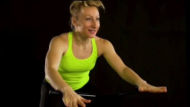 Chica en un trampolín de fitness sobre un fondo negro en una camiseta amarilla mujer en forma, cardio estilo de vida corporal, lindo club. Entrenador de bienestar, instructor de músculo de ropa deportiva disfrutar — Vídeo de stock