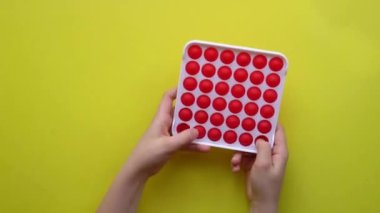 Sarı arka planda çocuk eğlencesi için popüler anti-stres oyuncağı. Renkli Fijit basit gamzeli popit sarı komik çocuklar, duyusal renk popüler rt, modern trend içinde çocuk üst görüntüsü oynuyor. El.