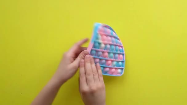 Popit Antistress-Spielzeug für Kinder Unterhaltung auf gelbem Hintergrund spielt ein Kind Draufsicht in farbigem Fijit einfach Grübchen Popit Spaß Kinder, Relief Pop populär rt, moderne Hand sensorische fein — Stockvideo