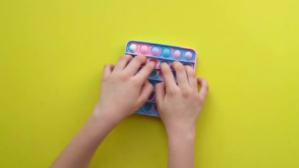Popit antistress παιχνίδι για τα παιδιά ψυχαγωγίας σε κίτρινο φόντο παίζει ένα παιδί top view σε χρωματιστό fijit απλό λακκάκι popit διασκέδαση παιδιά, αντι παιδιά ποπ ποπ, χαλαρώστε το παιδί. Κορυφαίο πρόστιμο υποβάθρου — Αρχείο Βίντεο