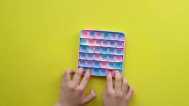 Sarı arka planda çocuk eğlencesi için popüler anti-stres oyuncağı renkli Fijit basit gamzeli popit oyuncağı, kadın itme pop, plastik trend. arkaplan iyi