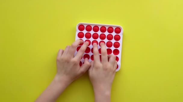 Popit Antistress-Spielzeug für Kinder Unterhaltung auf gelbem Hintergrund spielt ein Kind Draufsicht in farbigen Fijit einfach Grübchen Popit gelb Spaß Fidget, Kinder Farbe push rt, entspannen Gadget. Höchststrafe — Stockvideo