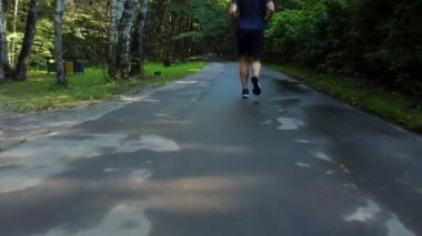 Parkta koşan bir sporcu, ormanda, meşe ağaçları yeşil çimenler atletik sporcuların hareketlerine ayak uydurup, refahı için koşuyor. enerji akıyor, uzaklık