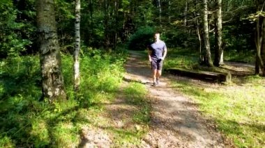 RUSSIA, MOSCOW - 26 Ağustos 2021 Parkta koşan bir sporcu açık havada, ormanın etrafında, meşe ağaçları genç yeşil çimenler atletik atlet doğası, spor gezisi hareketleri