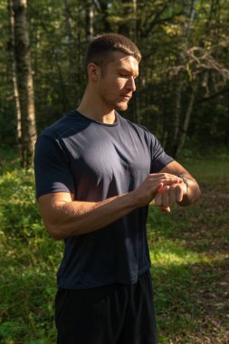 Bir erkek atlet parkta koşuyor, ormanın etrafında, meşe ağaçları yeşil çimenler genç dayanıklı atlet spor ormanlarında koşuyor, spor koşuyor, sağlık koşuları yapıyor, ağaçlar boş baharda, ayaklar