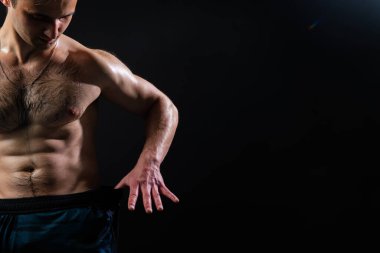 Siyah arka plandaki adam vücut geliştirme organlarında dambılları şişirmeye devam ediyor. Kaslı zindelik güçlü, üstsüz yaşam tarzı. Çekici, sportif, zinde. Basına ve ölçülere bak.