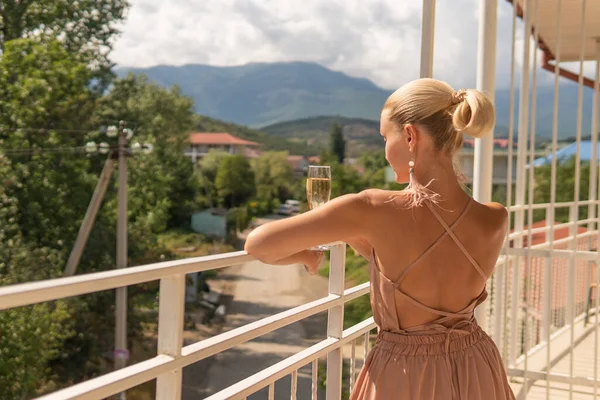 La ragazza è in piedi con champagne sul balcone di montagna e il cielo blu sullo sfondo bellezza balcone montagne stile di vita, persona adulta rilassarsi gioia, casa per il tempo libero. resort rilassante, hotel per vacanze — Foto Stock