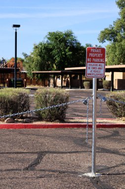 Metal zincir bariyeri, engellenmiş özel bir park alanından gelen araç harcamalarıyla ilgili kırmızı-beyaz uyarı levhası asılmış.