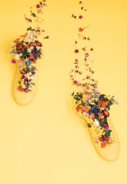Çiçeklerle dolu sarı bir arka planda sarı spor ayakkabı. Ayak izleri. İlkbahar minimalözet modern koncept.