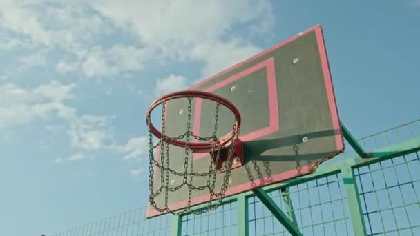 Chico atleta entrena con baloncesto en el patio de recreo, lanza la pelota en el ring 4k — Vídeo de stock
