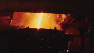 Dökümhanede bir kepçeden diğerine erimiş metal akışı. Fırında sıvı metal var. Sıvı metal üretim süreci. Endüstriyel fabrikada erimiş metal kalıbı. Yavaş çekim