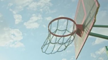 Çocuk parkında basketbol antrenmanı yapan bir sporcu topu ringe fırlatıyor.