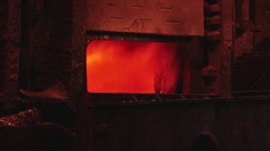 Dökümhanede bir kepçeden diğerine erimiş metal akışı. Fırında sıvı metal var. Sıvı metal üretim süreci. Endüstriyel fabrikada erimiş metal kalıbı. Yavaş çekim