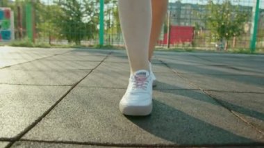 Spor ayakkabılı bir kadının bacakları kırsalda ya da çayırda yürürken..