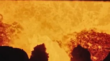 Dökümhanede bir kepçeden diğerine erimiş metal akışı. Fırında sıvı metal var. Sıvı metal üretim süreci. Endüstriyel fabrikada erimiş metal kalıbı. Yavaş çekim