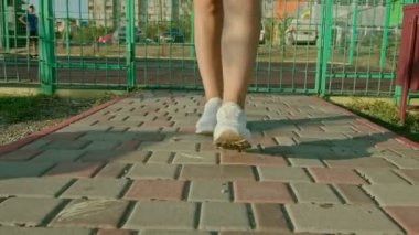 Spor ayakkabılı bir kadının bacakları kırsalda ya da çayırda yürürken..