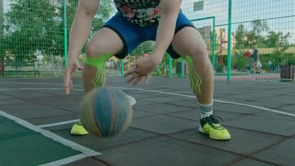 Kryvyi Rih Ucrania - 01.05.2021 chico atleta de entrenamiento con un baloncesto en el patio de recreo lento mo 4k 100fps — Vídeo de stock
