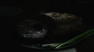 Siyah tabakta soğanlı et sunumu. Işıkla oyna.