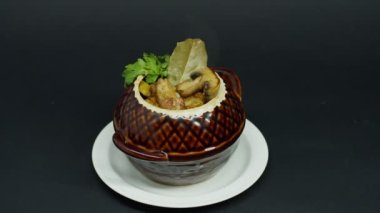 Bir tencerede rosto, bir tabak pirzola, patates ve mantarla birlikte, yemeğin sunumu.