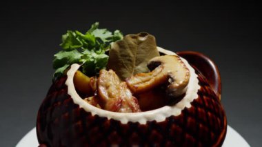 Bir tencerede rosto, bir tabak pirzola, patates ve mantarla birlikte, yemeğin sunumu.