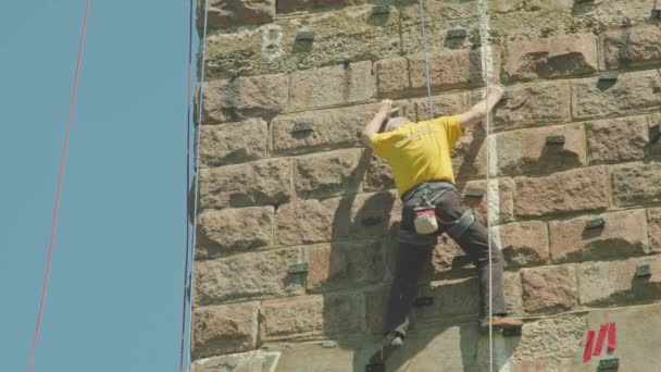 Kryvyi Rih, Ucrânia - 05.23.2021 um escalador de rocha sobe um suporte de pedra, uma coluna de uma ponte velha, um velho hóquei de alpinistas ProRes 422, bmpcc4k — Vídeo de Stock