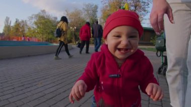 Anne küçük bir çocukla sokağa çıktı, kollarında onunla oynadı, çocuk ilk adımı attı ve yürümeyi öğrendi, mutlu bir aile, çocuk dünyayı öğrendi, Prores 422, bmpc4k.