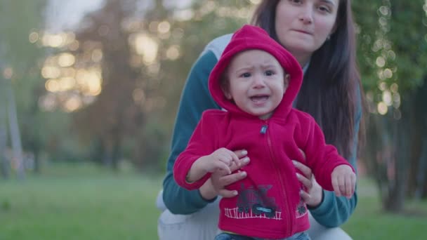 Mère est sortie dans la rue avec un petit enfant, joue avec lui dans ses bras, l'enfant fait les premiers pas et apprend à marcher, une famille heureuse, l'enfant apprend le monde, Prores 422, bmpcc4k. — Video