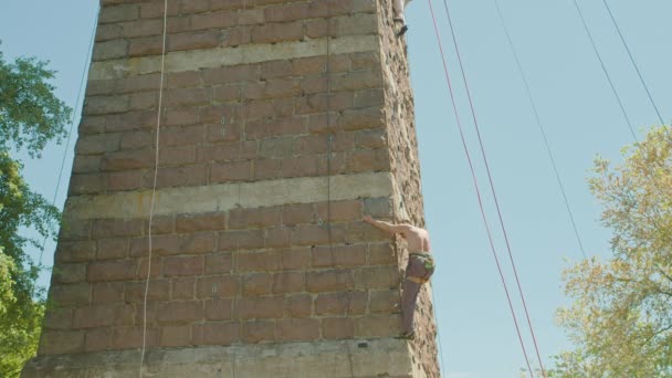 Kryvyi Rih, Ucrania - 05.23.2021 un escalador de rocas sube a un soporte de piedra, una columna de un puente viejo, un viejo escalador hockey ProRes 422, bmpcc4k — Vídeo de stock