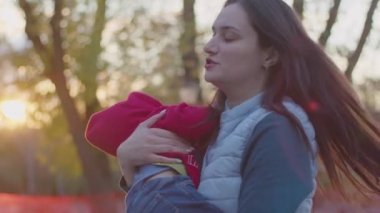 Anne küçük bir çocukla sokağa çıktı, kollarında onunla oynadı, çocuk ilk adımı attı ve yürümeyi öğrendi, mutlu bir aile, çocuk dünyayı öğrendi, Prores 422, bmpc4k.