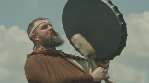 Een schuman man speelt een sjamanistische trommel, probeert het te laten regenen, aanbidt de oude goden en de natuur. de betekenis van de sjamaan in de natuur, prores 422, bmpcc4k — Stockvideo