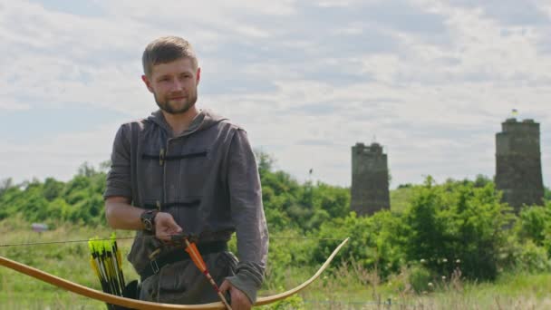 Mladý muž vystřelí luk na terč, v přírodě, a zasáhne cíl, šíp prorazí terč k letu, zatáhne tětivu luku pevně pro výstřel. Prores 422 — Stock video