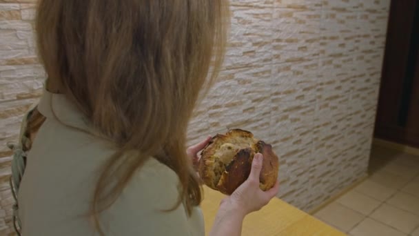 Werbefotos, ein Mädchen backt Brot, sie schneidet es mit einem Messer, bricht es mit den Händen, erschnüffelt es, es riecht wunderbar. Verbindung mit Kindheit und Elternhaus. Prospekt422. — Stockvideo