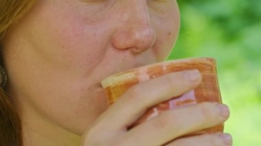 Yazın genç bir kız sıcak çay içer, salıncakta oturur, bahçesinde, çay en iyi sıcakta yardımcı olur, Prores422