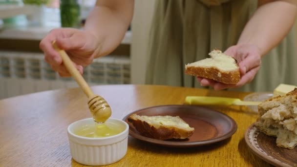 Nagranie z reklamy, młoda dziewczyna kroi chleb nożem, rozkłada kanapkę z masłem i nalewa miód, tańczy i je kanapkę, uśmiecha się do kamery. Prores422 — Wideo stockowe