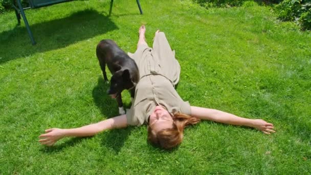 Yazın genç bir kız bir köpekle bahçede oynar, yalarken ve eğlenirken onu çizer. Prores422. — Stok video