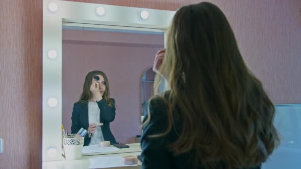 Дівчина новинний ведучий фарбує себе і використовує спрей для волосся перед телевізійною трансляцією — стокове відео