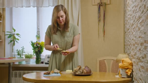 Reklamní záběry, mladá dívka krájí chléb nožem, rozmaže sendvič s máslem a nalije med, tančí a jí sendvič, usmívá se do kamery. Prores422 — Stock video