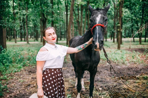 白いブラウスとスカートに馬と夏の森の中の若い笑顔のブロンドの写真 — ストック写真