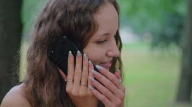 Reklam çekimi, parktaki genç bir kız siyah elbiseli bir bankta oturuyor ve telefonda konuşuyor..