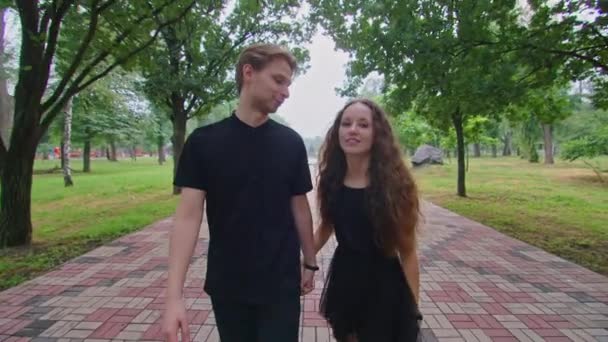 Um jovem casal, um cara e uma menina estão correndo ao longo do beco no parque, abraçando, brincando, mostrando sentimentos um ao outro. — Vídeo de Stock