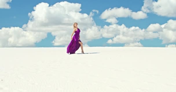 Cinematische slow motion van een vrouw die over een zandduin loopt. Barefoot vrouw reiziger in een jurk zwaaiend in de wind op het golvende oppervlak van de zandwoestijn met een wolk op de achtergrond. 4K Scenic — Stockvideo