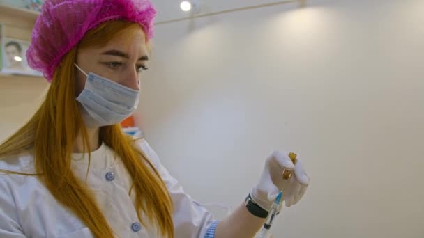 Vue macro des mains des cosmétologues en gants roses mélangeant du matériel de cosmétologie en seringue pour une injection de charge faciale anti-âge. Procédure d'injection de beauté. — Video