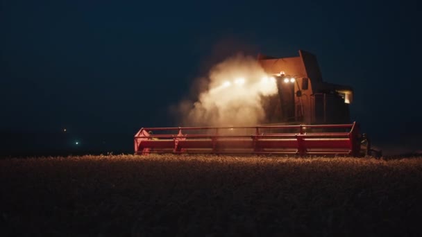 Харвестер ночью в поле собирает пшеницу, редкие кадры, напоминающие стальную руку Господа. — стоковое видео