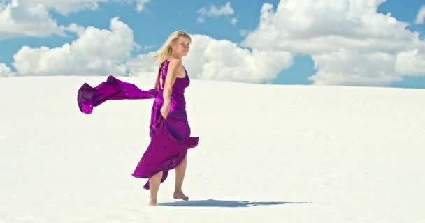 Cinemática cámara lenta de una mujer caminando sobre una duna de arena. Viajante descalza en un vestido balanceándose en el viento sobre la ondulante superficie del desierto de arena con una nube en el fondo. 4K Escénico — Vídeos de Stock