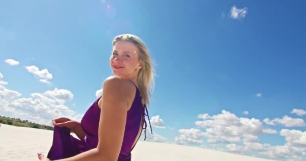 Кинематографическое замедленное движение женщины, идущей по песчаной дюне. Босоногая женщина-путешественница в платье, раскачивающемся на ветру по волнистой поверхности песчаной пустыни с облаком на заднем плане. 4K Scenic — стоковое видео