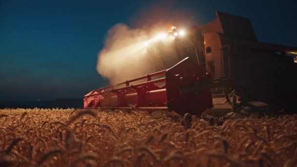 Kombajn v noci na poli sklízí pšenici, vzácné záběry, připomínající ocelovou ruku Páně. — Stock video