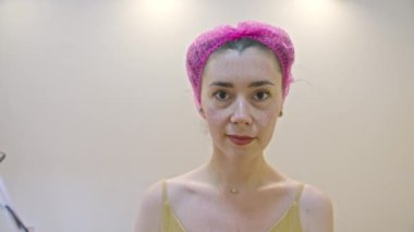 Ameliyattan sonra güzellik muayenehanesinde dikilirken kameraya bakan kendinden emin, genç Avrupalı bir kadın..